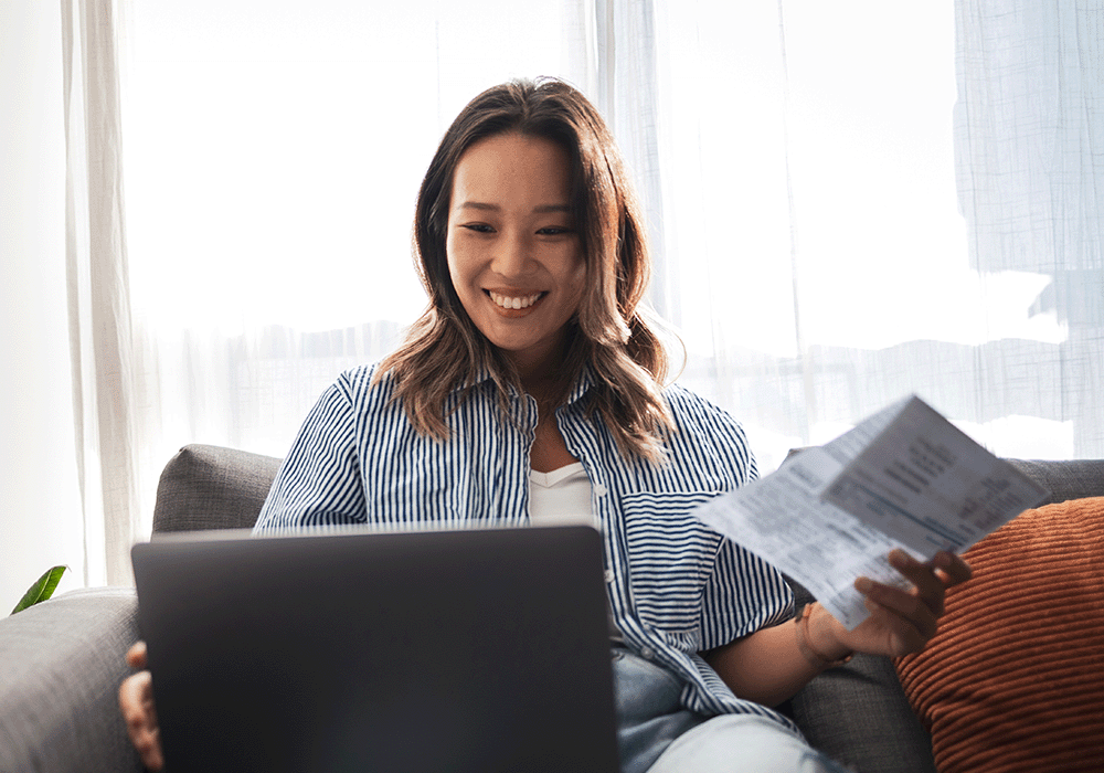 Woman looking at her computer and holding financial documents